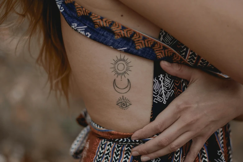 a woman holding her belly tattoo with her hands