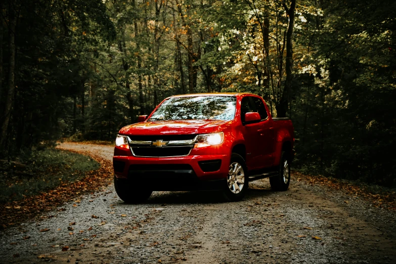 a red pickup truck drives down a country road