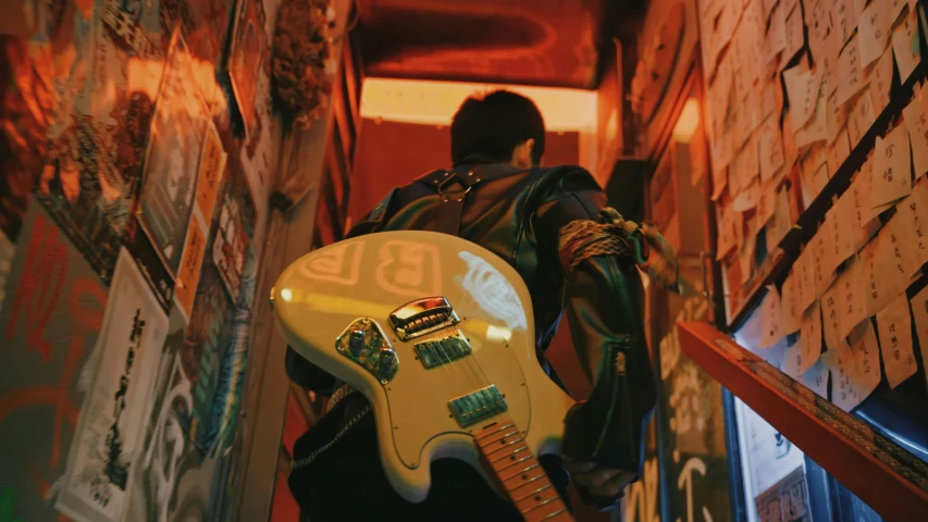 a person with a yellow guitar next to a wall of papers