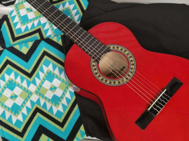 a red guitar sits on a colorful pillow