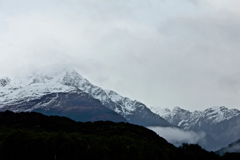 a snow covered mountain in the background under cloudy skies