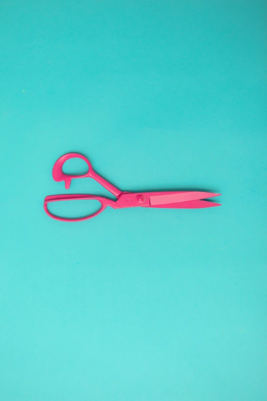 there is a pair of pink scissors sitting in front of green