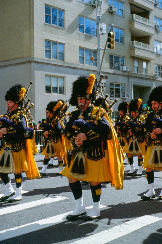 people in uniform marching down a street with pipes