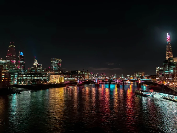 a river scene with lights in the water and the lights of other buildings are bright and shine brightly at night