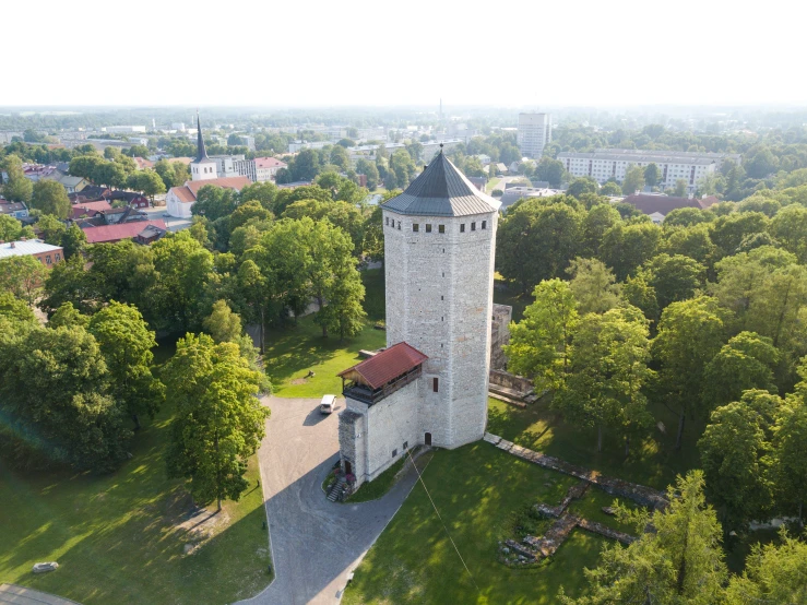 an old, gray tower surrounded by trees in the middle of town