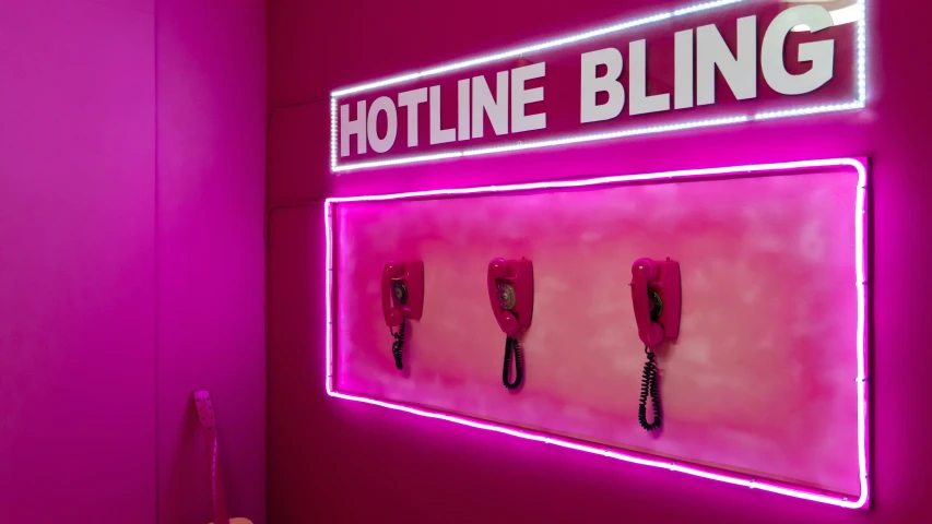 the neon sign has four cellphones mounted in the wall