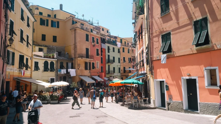 a city street with people, tables and umbrellas