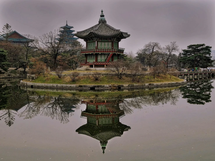 a small asian pavilion sits in the middle of some water