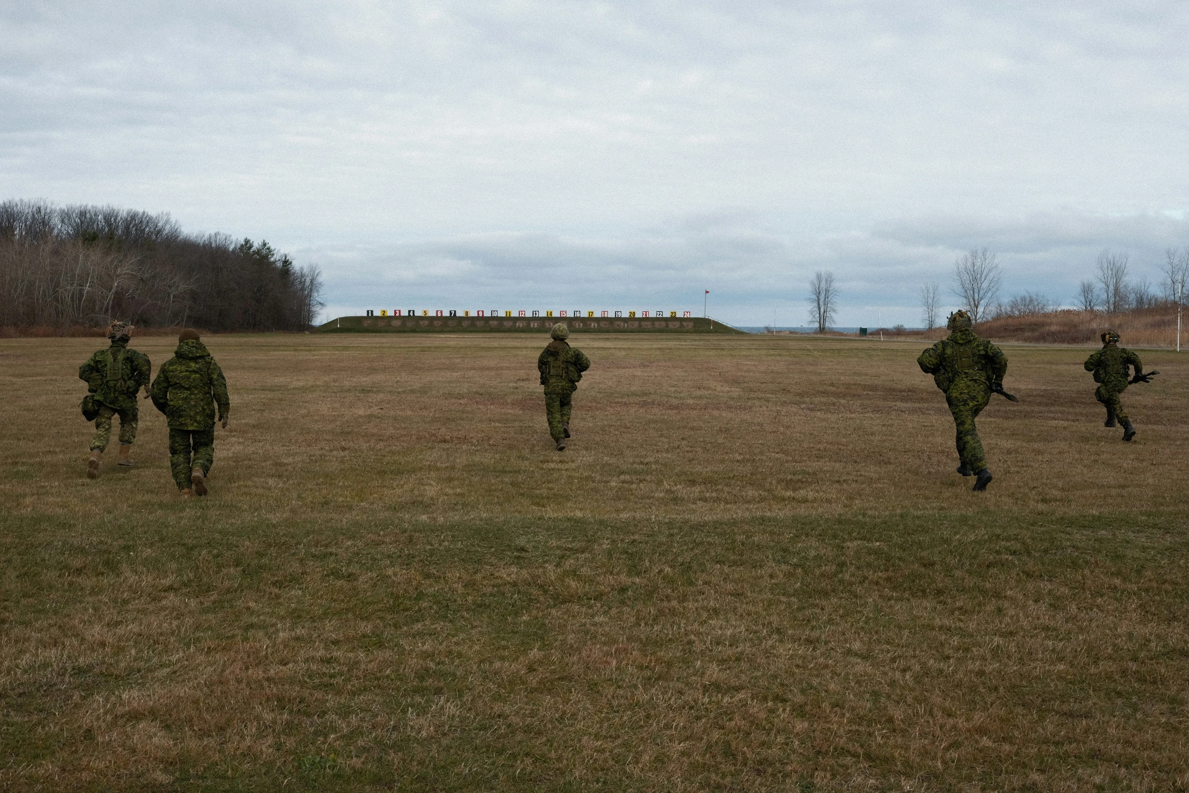 soldiers run through the grass to the military band