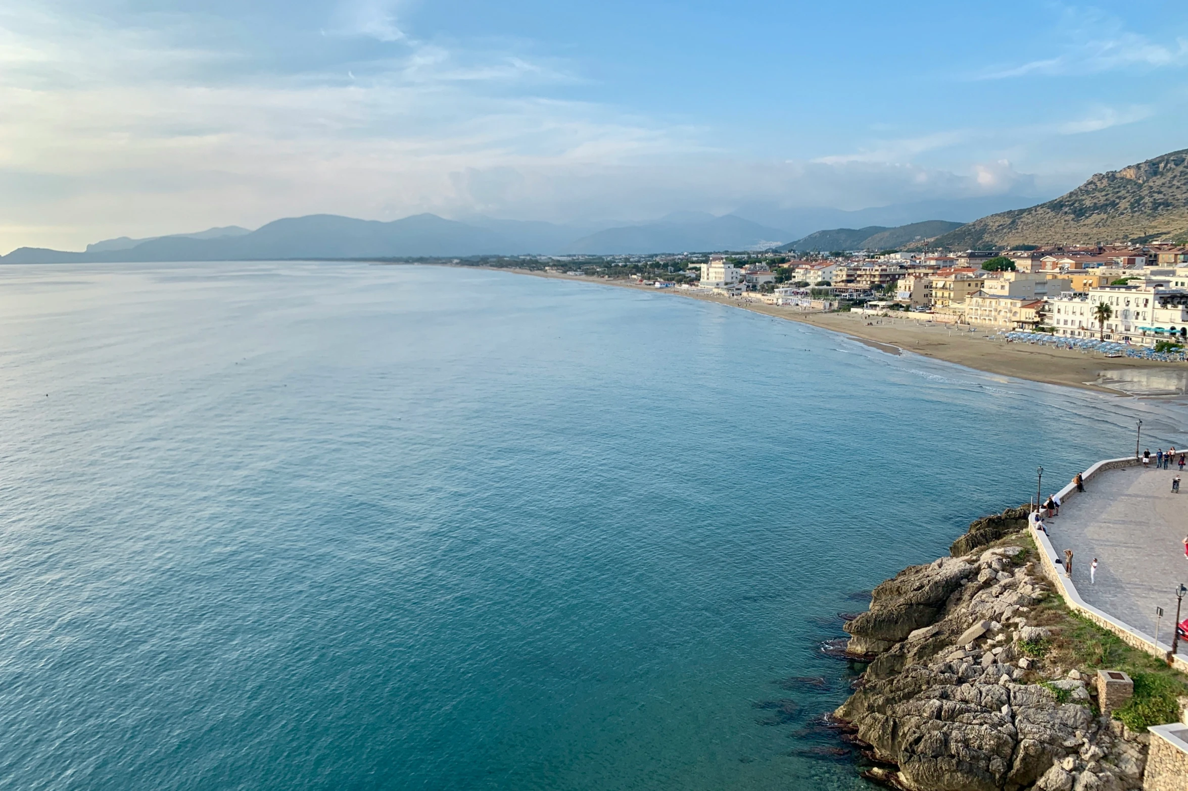 a beach with people walking along it, near the water