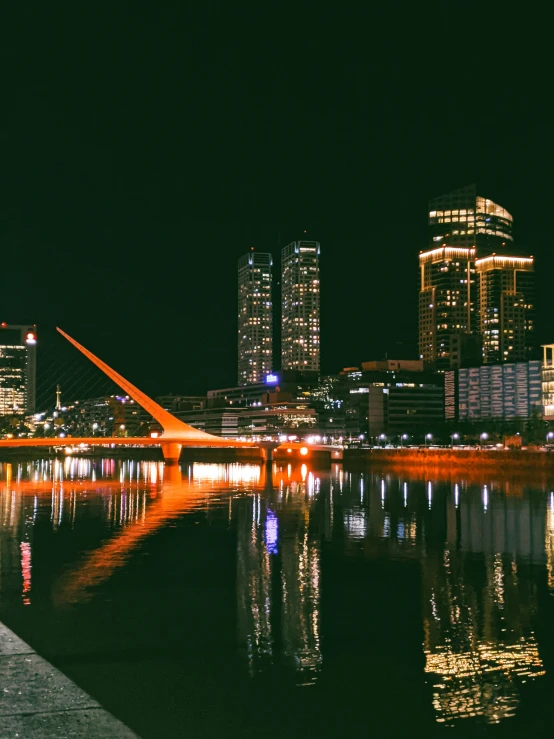 city skyline seen from the water with its lights reflecting off in the river