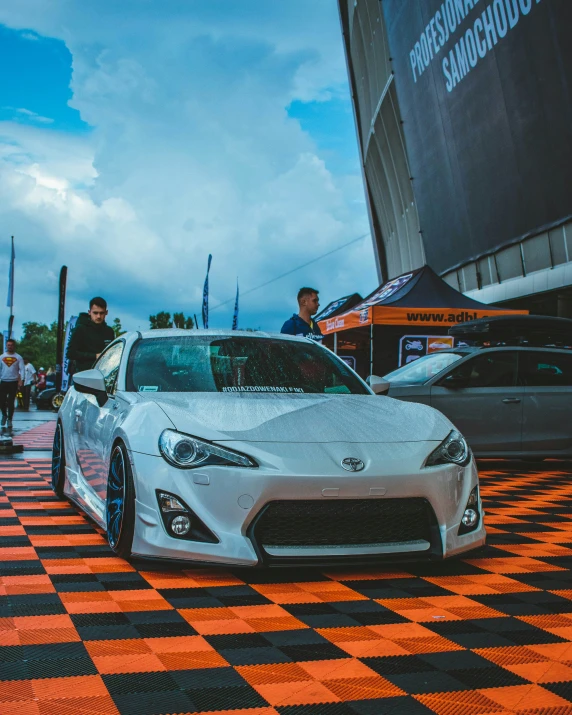 a grey car sitting in front of a red checkered floor