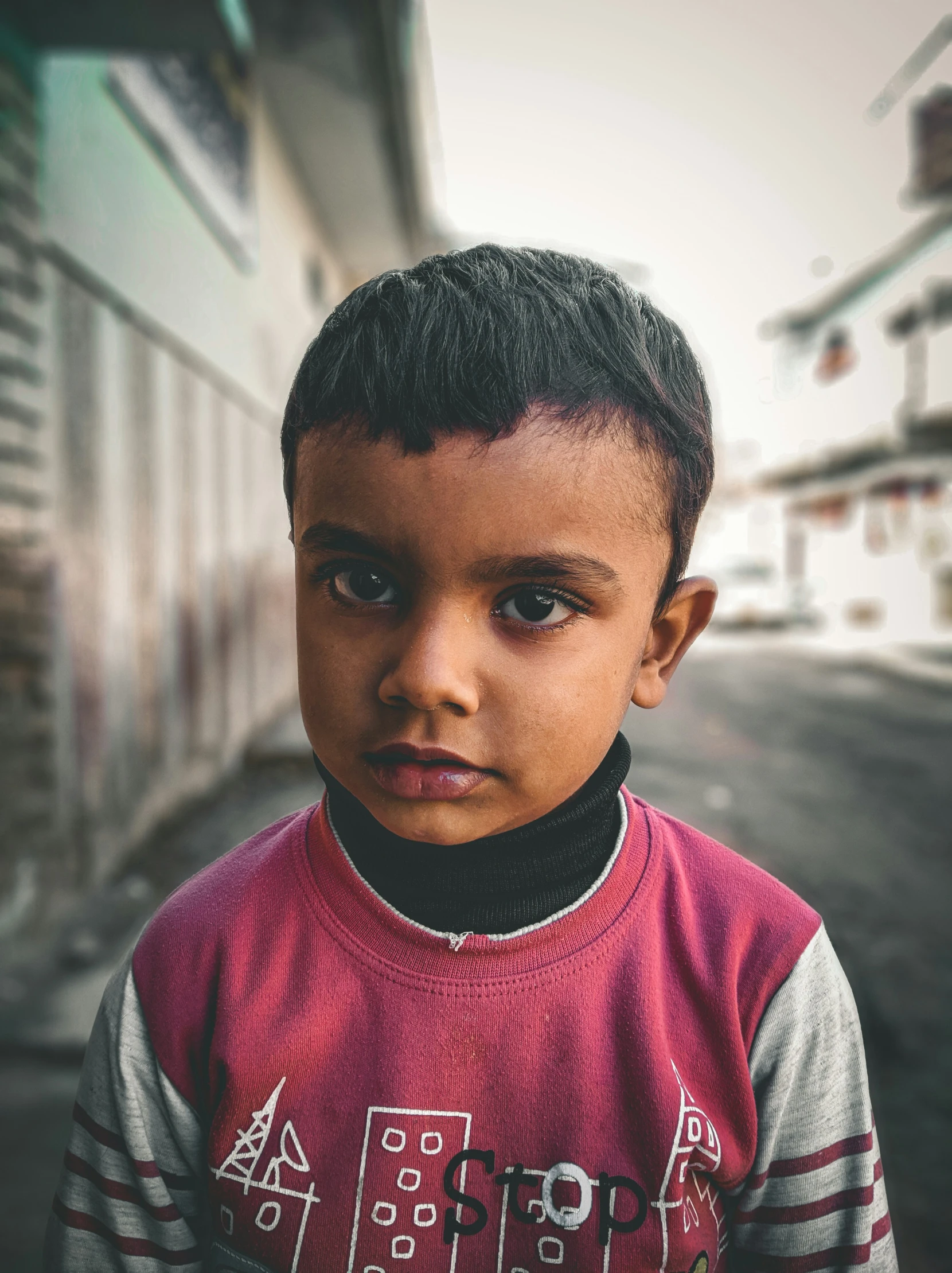 young black boy in red sweater near buildings