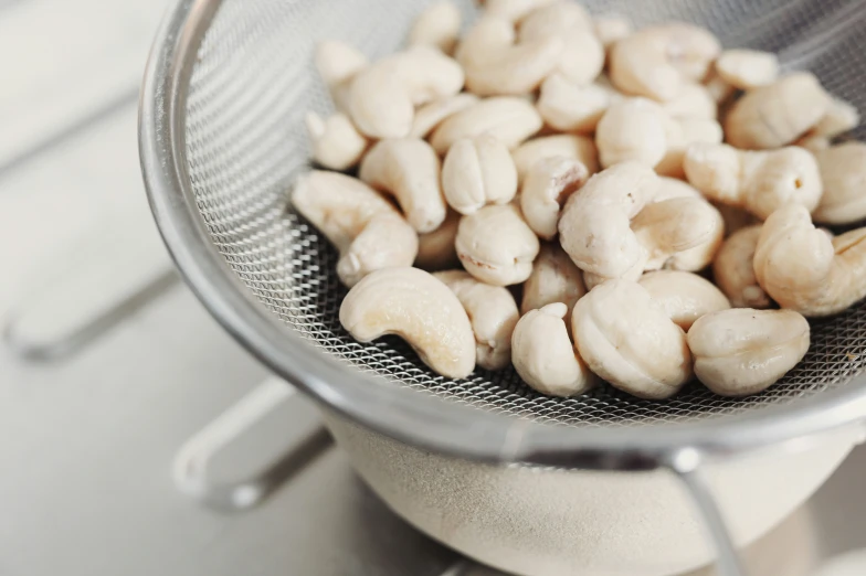 a white bowl filled with cashews and sitting on top of a stove