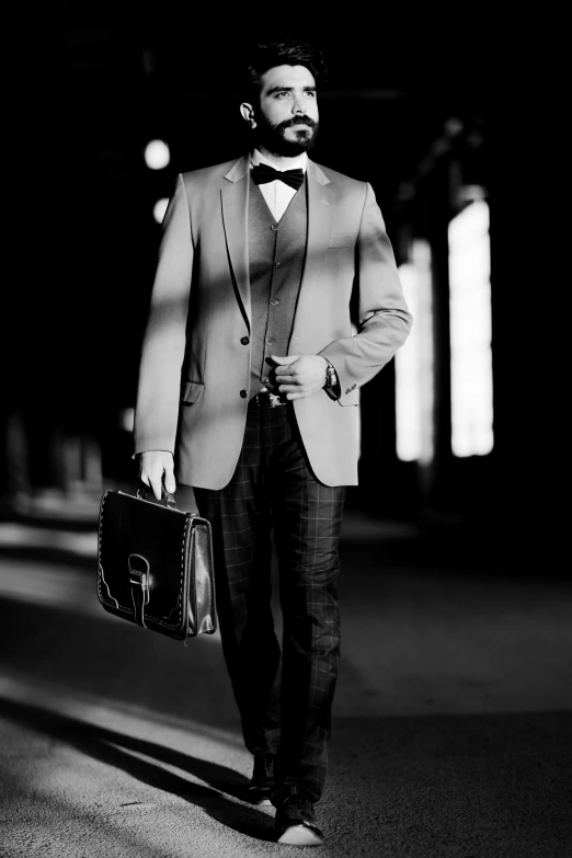 a man in a tuxedo and bow tie holding his briefcase