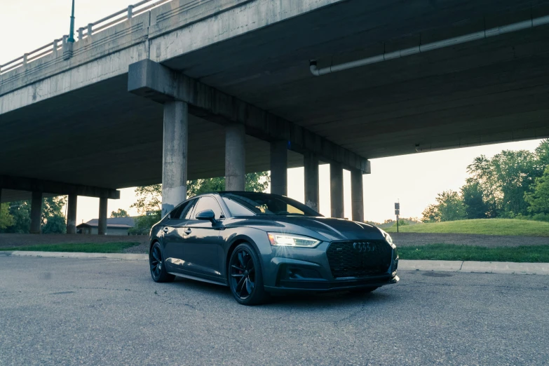 a black sports car sits on the parking lot underneath a bridge