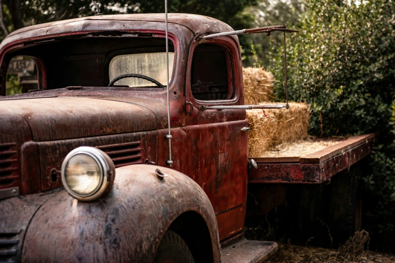 an old truck parked with hay bales in the bed