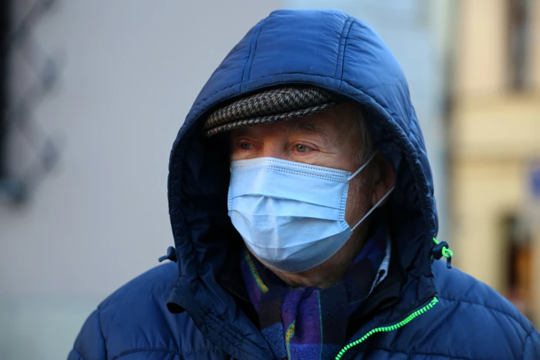 a man wearing a blue coat and hood with a face mask