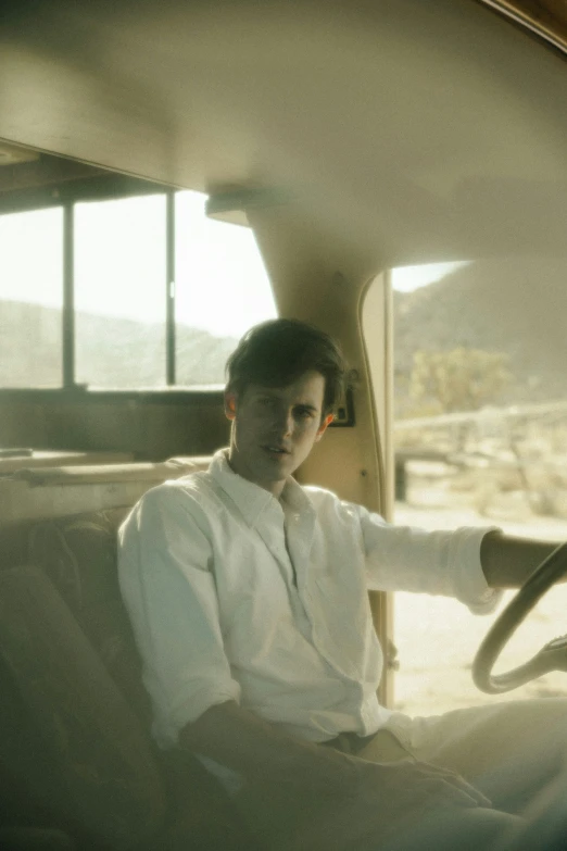 a man sitting in a car and holding the steering wheel