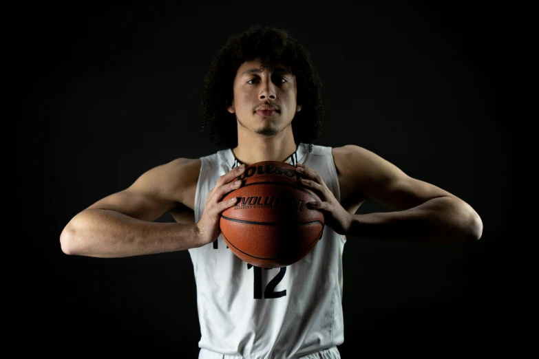 a young man holds a basketball up to his face