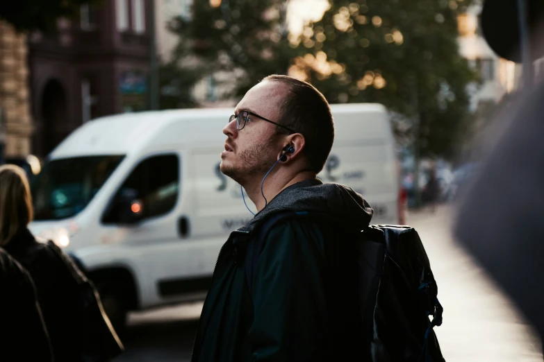 a man with ear buds and headphones on a street