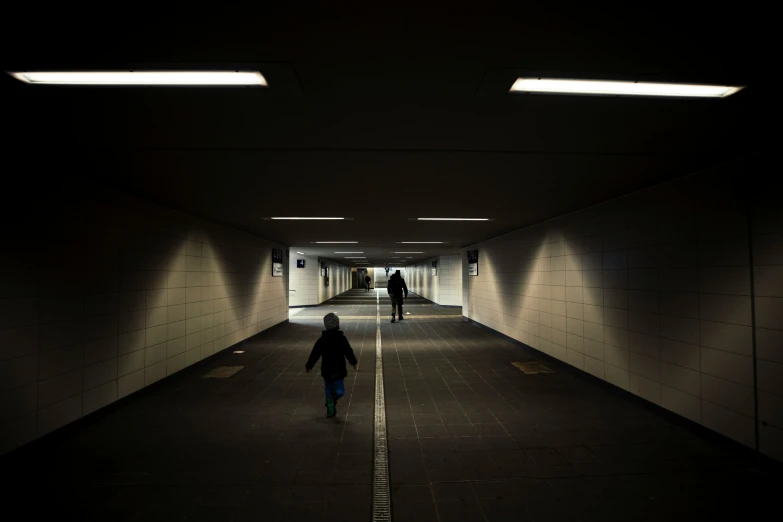 people are walking in the middle of a long dark tunnel
