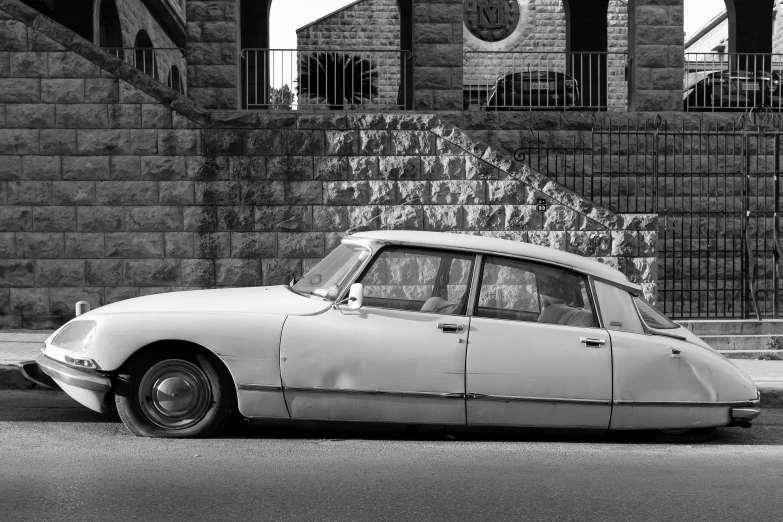 a vintage car is parked in front of an old brick wall