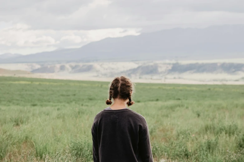 a woman standing in an open green field