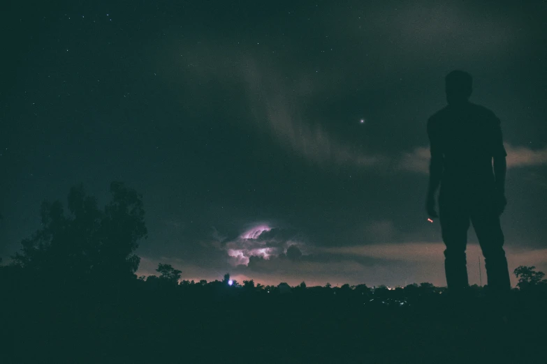 a man standing on a hill looking at fireworks in the sky