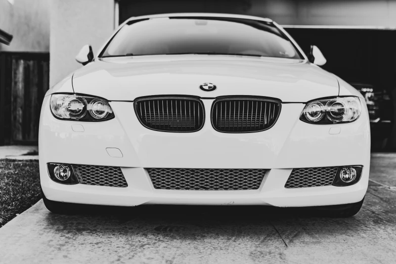 the front of a white bmw car parked outside