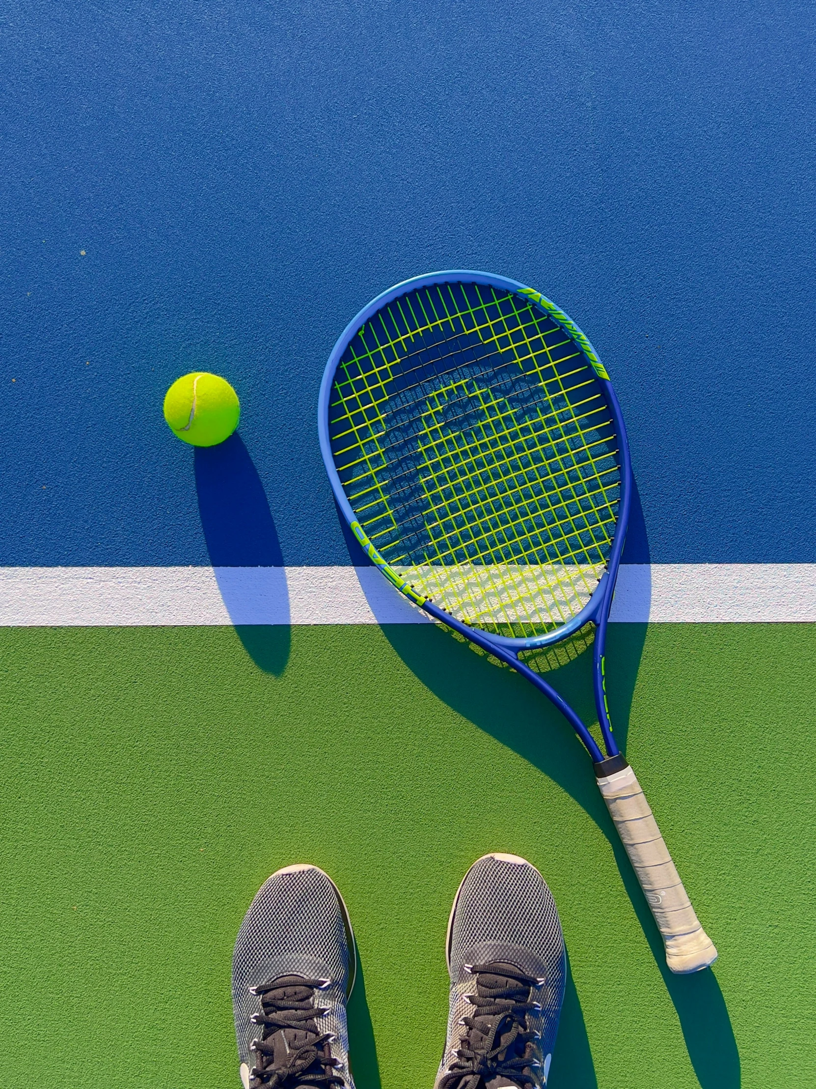 someone's feet on a tennis court next to a tennis ball