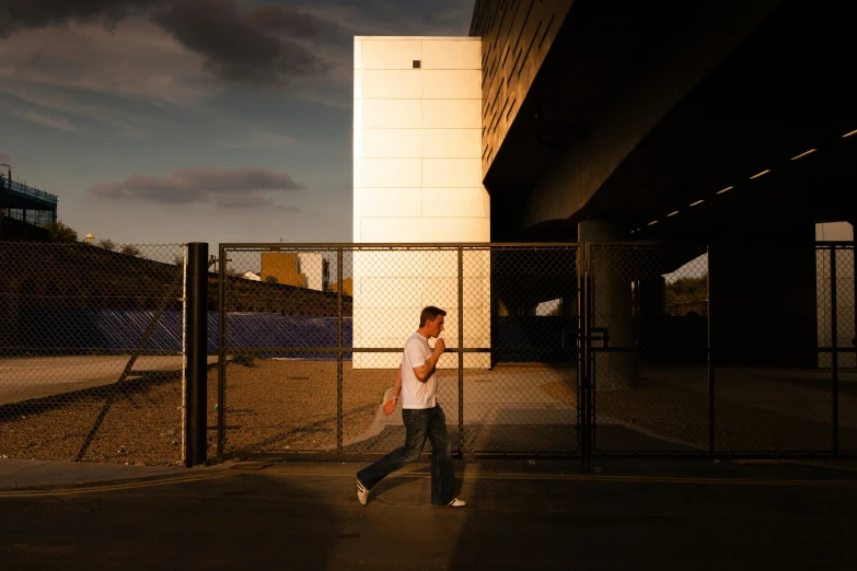 a man in jeans stands alone near a fence