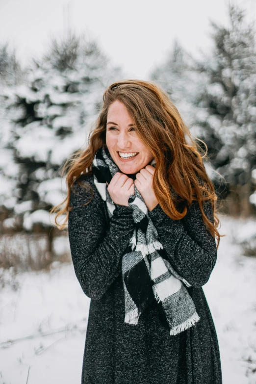 a beautiful young woman laughing with snow on her feet