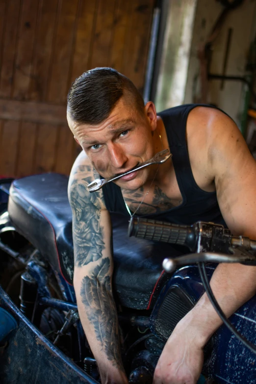 a man with tattoos is sitting on an antique motorcycle