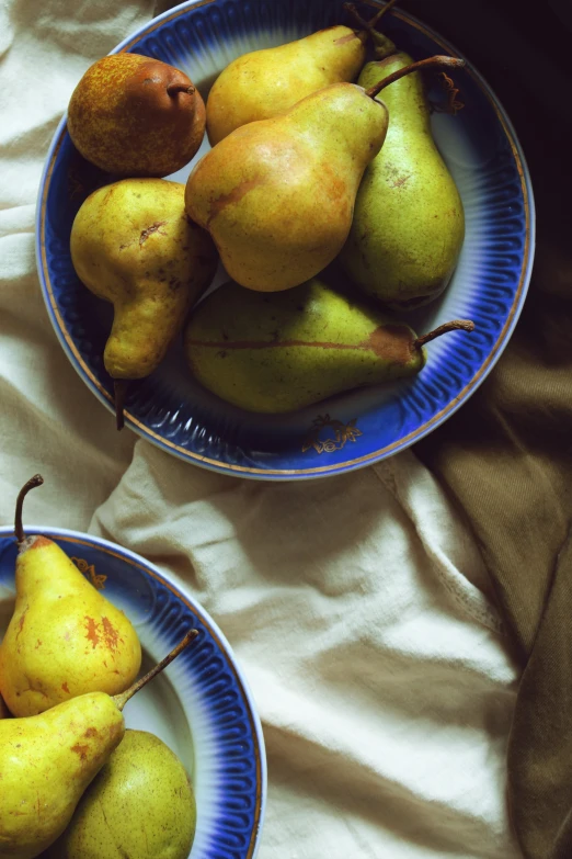 two plates filled with pears and potatoes on top of a bed