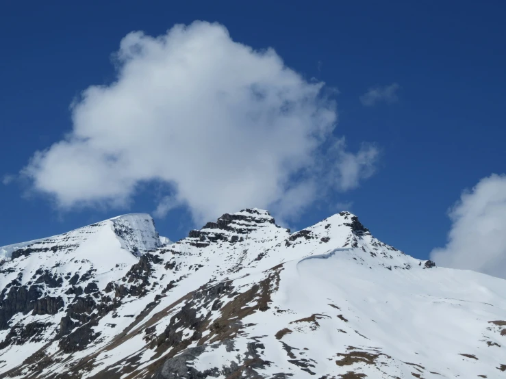 a very snowy mountain is in front of some clouds