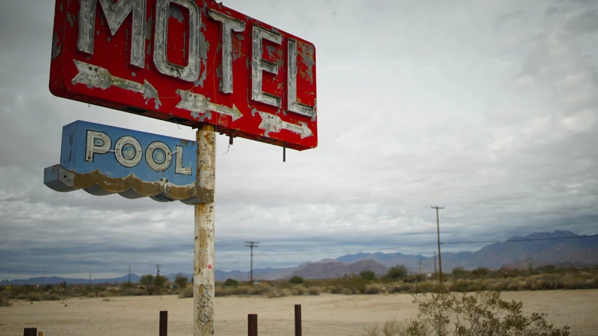 the large motel sign has a few signs hanging off it