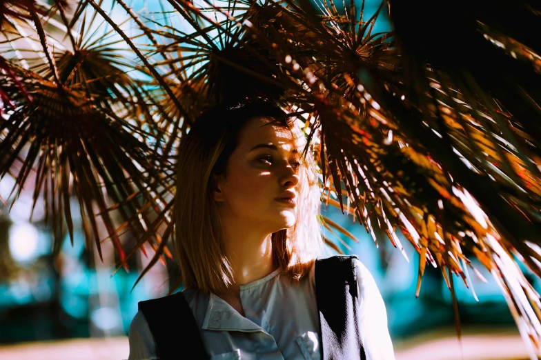 a woman in white shirt next to plant and trees