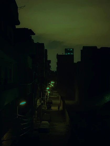 an empty city street at night with buildings lit up in green