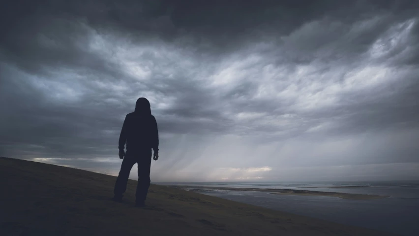 a person standing under a very cloudy sky