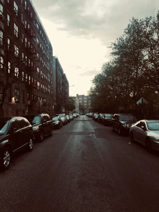 cars parked on a narrow city street at sunset