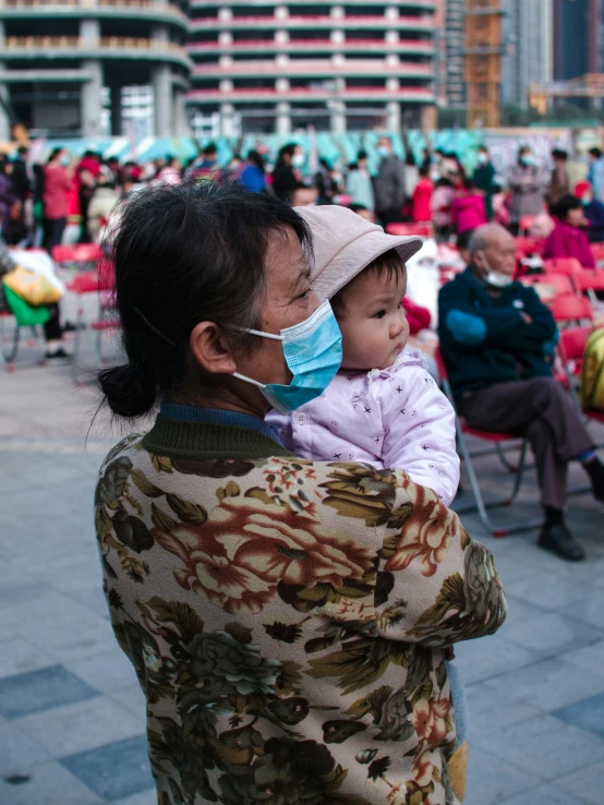 a lady that is wearing a surgical mask while holding her child