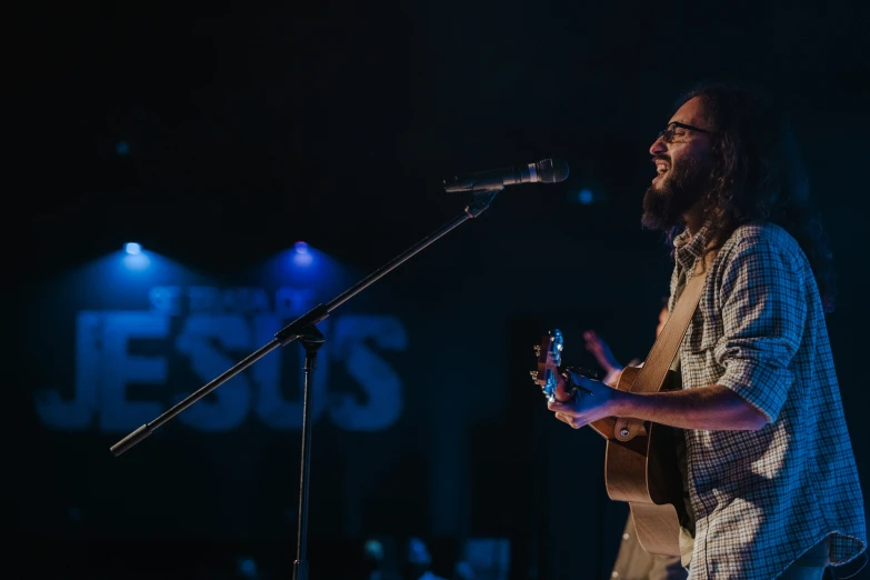 a bearded man standing in front of a microphone