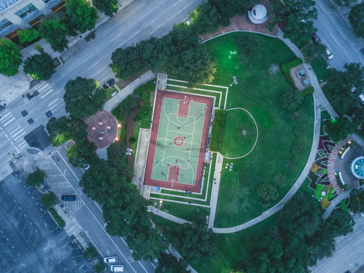 an aerial view of a tennis court in the middle of a park