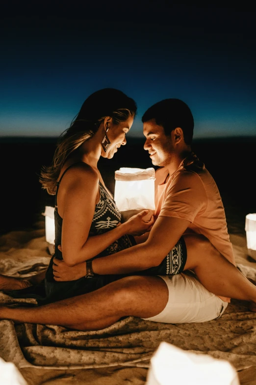 a young couple siting on a bed at night looking at each other