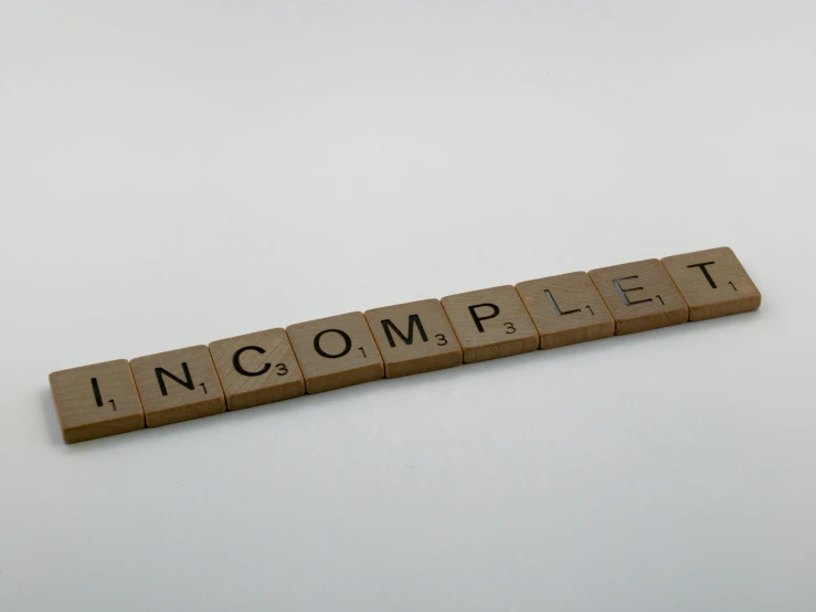 a scrabble type wooden block that reads incomplete