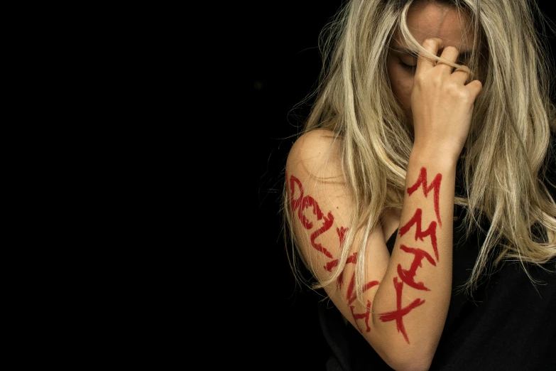 woman with long blonde hair covered in red painted lettering