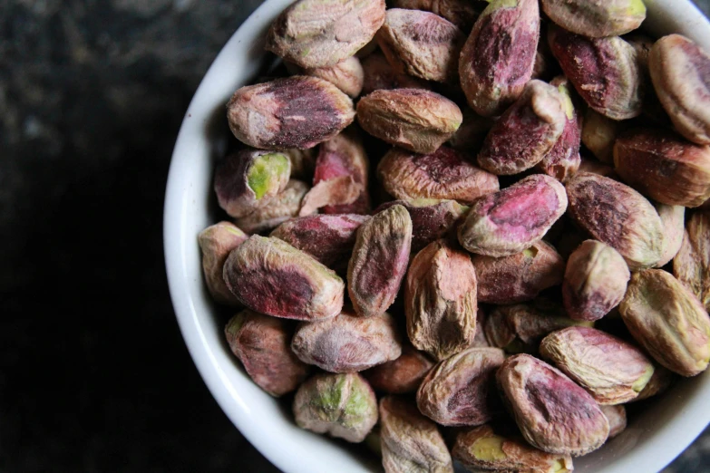 a bowl filled with pink almonds sitting on top of a table