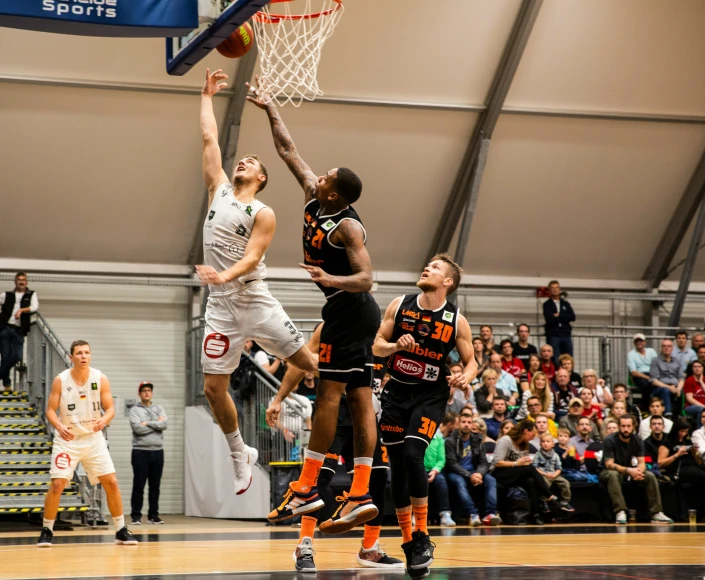 men in basketball uniforms with people watching from the sidelines