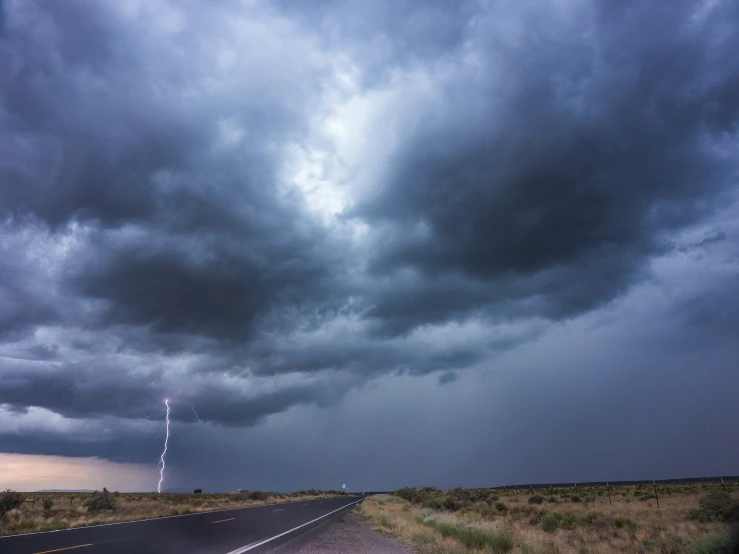 storm clouds hover over an empty highway at dusk